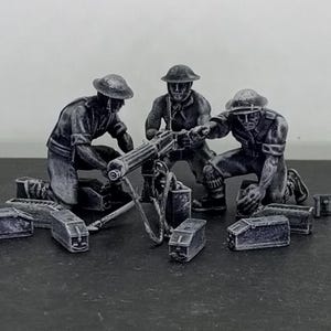 May include: A monochrome model depicting three soldiers operating a machine gun. The figures, in helmets and uniforms, are positioned around the gun. Several ammunition boxes are placed nearby. The scene evokes a historical military theme.