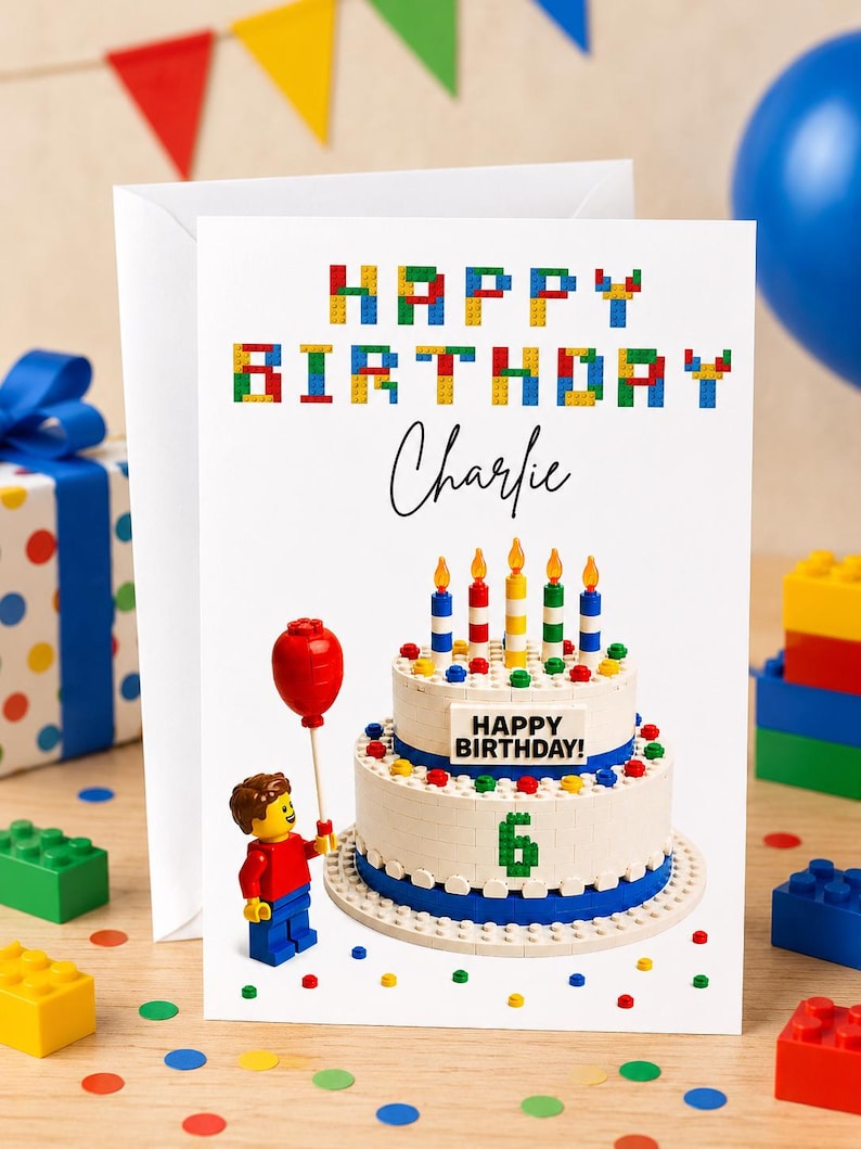 May include: A birthday card with a Lego theme, featuring the text "Happy Birthday Charlie". The card shows a cake with candles and a Lego figure with a red balloon. Colourful confetti and Lego bricks are scattered around the scene.