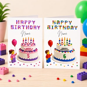 May include: Two birthday cards with Lego-themed designs. Each card features a cake with candles, a Lego figure holding a balloon, and the words "Happy Birthday" in colourful block letters. One card shows the number 5, the other shows the number 6.