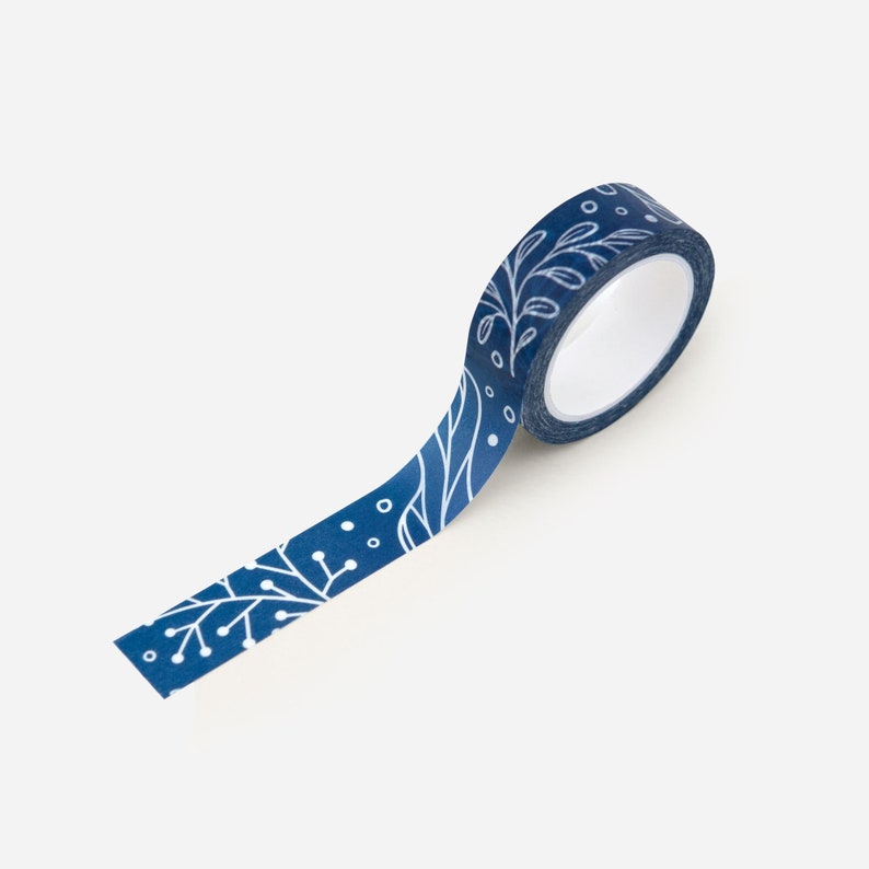 May include: A roll of blue washi tape with a white floral pattern. The tape is rolled up and the end is hanging down.