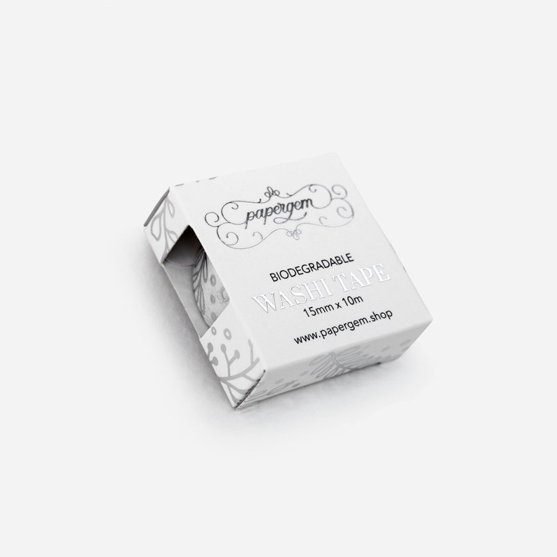 May include: A white cardboard box with a silver design and the text "BIODEGRADABLE WASHI TAPE 15mm x 10m www.papergem.shop" printed on it.