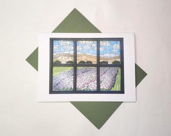 May include: A greeting card with a mosaic-style illustration of a window. The window shows a landscape with a blue sky, clouds, and a lavender field. The card is on a white background with a green envelope.