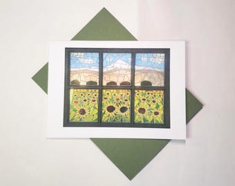 May include: A greeting card with a mosaic design of a window looking out onto a sunflower field. The window frame is black, and the sky is blue with white clouds. The card is on a white background, with a green envelope.