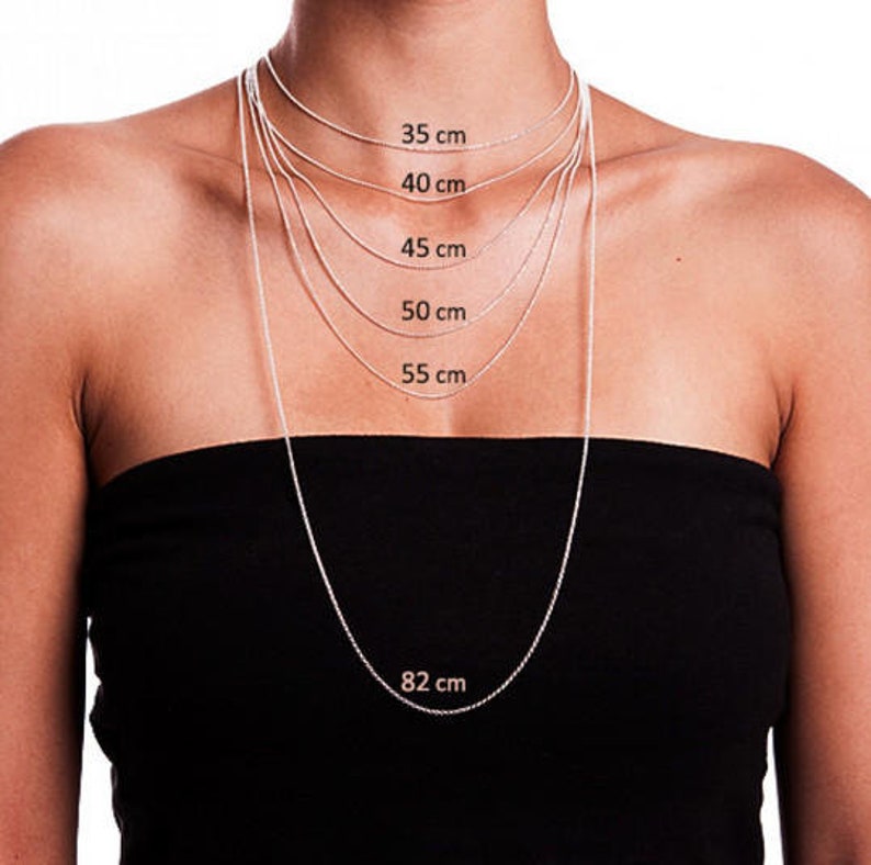 May include: Silver chain necklaces of various lengths, displayed on a person. The lengths are labeled in centimeters: 35 cm, 40 cm, 45 cm, 50 cm, 55 cm, and 82 cm. The necklaces are shown against a black strapless top.