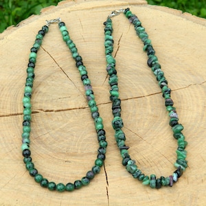 Könnte beinhalten: Zwei grüne Edelsteinketten mit silbernen Verschlüssen. Eine Kette hat runde Perlen und die andere hat unregelmäßig geformte Perlen.