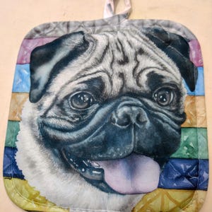 May include: A pot holder with a colourful striped background featuring a close-up of a pug's face. The pug has a light brown and white coat, a black nose, and a pink tongue sticking out. The text "Amy Calla" is visible in the bottom right corner.