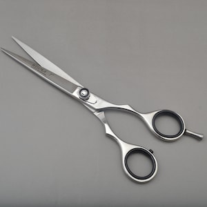 May include: Silver hairdressing shears with a black handle and the word "HIGOKA" engraved on the blade.