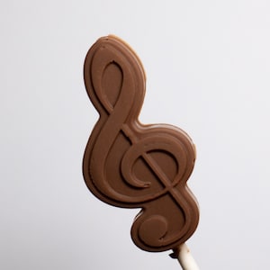 May include: A brown chocolate lollipop shaped like a treble clef.