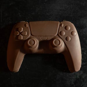 May include: A chocolate replica of a video game controller. The controller is brown and has all the buttons and joysticks of a real controller.