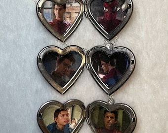 May include: A silver heart-shaped locket necklace with three sets of lockets. Each locket features a different image from the Spider-Man movies. The top locket shows Spider-Man in his red and blue suit. The middle locket shows a close-up of Spider-Man's face. The bottom locket shows Spider-Man in a red and blue suit with a black spider logo.