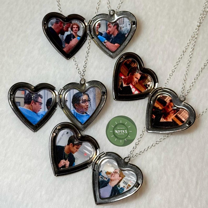 May include: Heart-shaped silver lockets with photos inside, displayed on a white surface. Some lockets are open, revealing the pictures. Each locket hangs from a delicate silver chain. The photos appear to be of people in various settings.