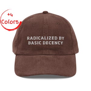 May include: A brown corduroy baseball cap featuring the embroidered text "RADICALIZED BY BASIC DECENCY" in white. The cap has a curved peak and a small button on top. A red circle with the words "+4 Colors" is in the upper left corner.