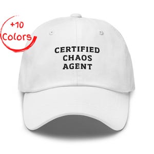 May include: White baseball cap with the text "CERTIFIED CHAOS AGENT" in black. The cap has a curved brim and an adjustable strap. A red circle with the words "+10 Colors" is in the upper left corner.
