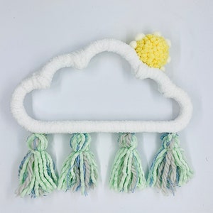 May include: White yarn cloud with a yellow yarn sun on top and five green and blue yarn tassels hanging from the bottom.