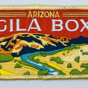 May include: A yellow embroidered patch with a red background and the text "ARIZONA GILA BOX" in white. The patch features a stylized image of a river winding through a desert landscape.