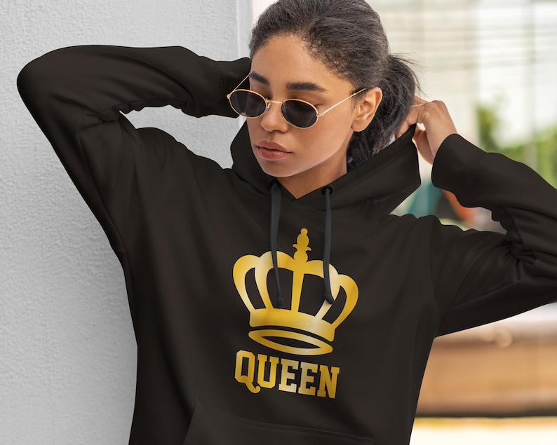 May include: Black hoodie with a gold crown graphic and the word "QUEEN" printed below. The hoodie has a drawstring hood and long sleeves. The graphic is centered on the front of the sweatshirt.