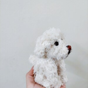 May include: A white fluffy crocheted dog toy with black eyes and a brown nose.