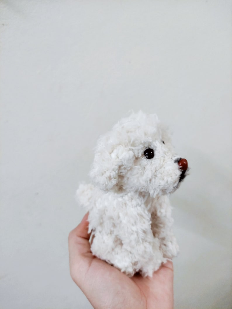 May include: A white fluffy crocheted dog toy with black eyes and a brown nose.