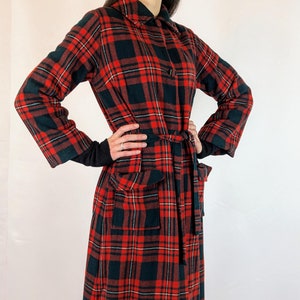 Peut inclure: Une longue robe de chambre en tissu écossais rouge et noir avec un col, des manches longues et une ceinture à nouer.