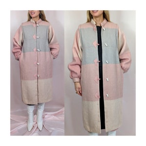 Op de afbeelding: Een lange, roze, grijze en witte gestreepte wollen jas met een mandarijnsluiting en knopen. De jas heeft lange mouwen en een losse pasvorm.