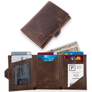 May include: A brown leather wallet with a snap closure and multiple card slots. The wallet is open and shows a driver's license, credit cards, and cash. The wallet has the brand name "TRUSADOR" printed on the front.