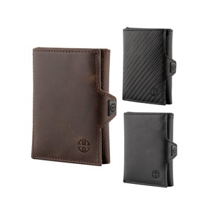 May include: Three different styles of wallets. One is brown leather, one is black leather, and one is black with a carbon fiber pattern. All three wallets have a small metal logo on the front.