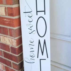 May include: White wooden sign with black lettering that reads "HOME" and "home sweet home" in cursive script.