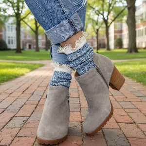 May include: A pair of gray suede ankle boots with a block heel and a zipper detail. The boots are paired with blue and white patterned socks with a lace trim, and blue jeans.