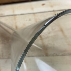 May include: A clear glass funnel with a wide top and a narrow spout. The funnel is made of thick glass and has a smooth, polished finish.