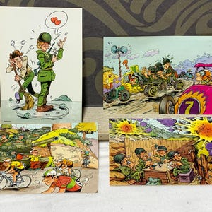 Op de afbeelding: Vier vintage ansichtkaarten met cartoon illustraties. Eén toont een soldaat met harten boven zijn hoofd, een andere toont soldaten in voertuigen, een derde toont fietsers en de laatste toont soldaten die kaarten spelen.