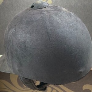 May include: A black riding helmet with a smooth, slightly textured surface. The helmet has a small, round vent on the top.