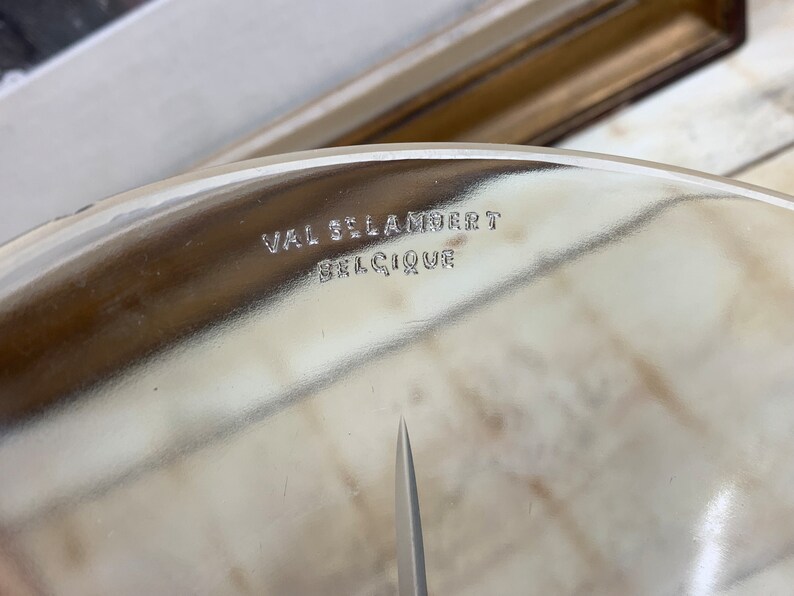 May include: Close-up of a clear glass plate with the inscription "VAL ST LAMBERT BELGIQUE" etched on the bottom.