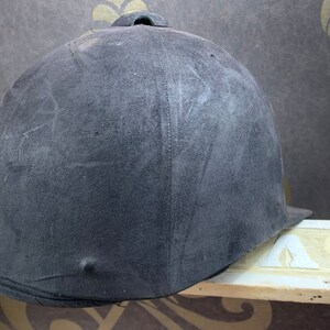 May include: A black riding helmet with a smooth, slightly textured surface. The helmet has a seam down the center of the back.