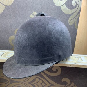 May include: A dark gray riding helmet with a black brim. The helmet has a smooth, slightly textured surface.