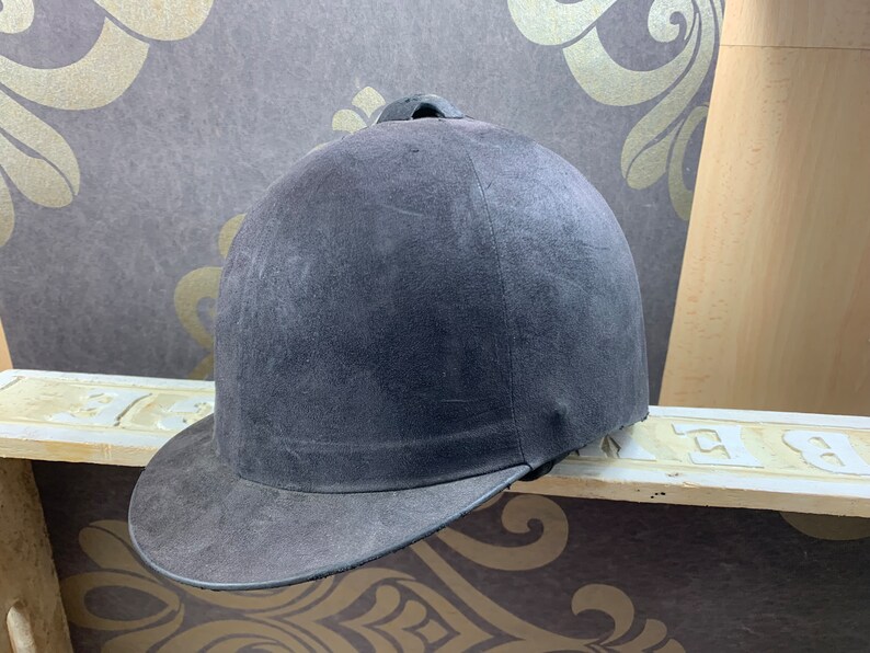 May include: A dark gray riding helmet with a black brim. The helmet has a smooth, slightly textured surface.