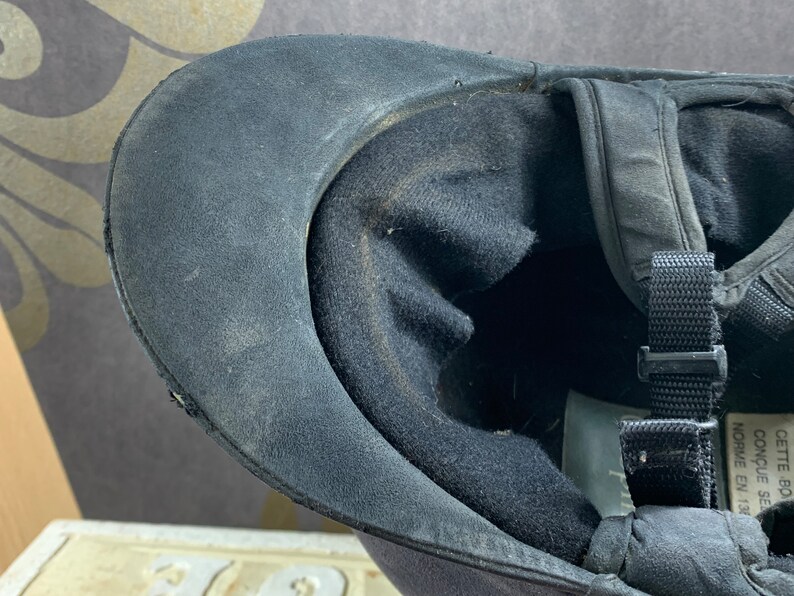May include: Black riding helmet with a black strap and the text "CONCUE SE NORWE EN 1204" in white.