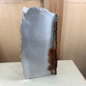 Op de afbeelding: Een witte keramische vaas met een bruine glazuur aan één kant. De vaas heeft een onregelmatige vorm en een ruwe textuur.