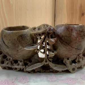 Op de afbeelding: Een gegraveerd stenen dubbel inktpot met een bloemmotief. De inktpot is gemaakt van donkerbruine en grijze steen met een gladde afwerking. De inktpot is een traditioneel Chinees ontwerp.