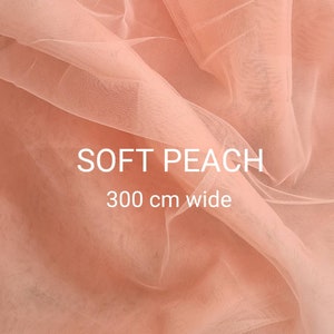 May include: Soft peach tulle fabric, 300 cm wide. The fabric is a light peach colour and has a soft, delicate texture.