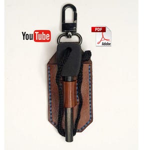 May include: A brown leather fire starter kit with a black handle and a metal striker. The kit includes a leather sheath with blue stitching, a black lanyard, and a metal carabiner. The YouTube and Adobe PDF logos are visible.