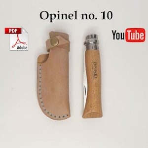 Puede incluir: Una navaja Opinel no. 10 con mango de madera clara y virola de bloqueo metálica, junto a una funda de cuero beige con cierre de botón a presión de latón y costuras claras a lo largo del borde curvo.