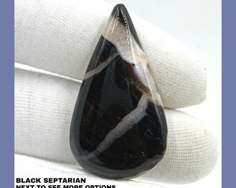 May include: A black septarian pendant with white and brown veins. The pendant is teardrop shaped and has a polished finish.