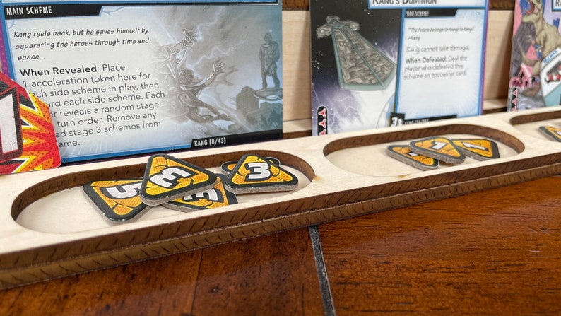 May include: A wooden game board with two slots for holding game pieces. The slots are filled with yellow and black triangular tokens with the number "3" printed on them. The board has a brown wooden frame with a decorative pattern.