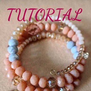 Könnte beinhalten: Ein mehrsträngiges Armband mit Pfirsich-, weißen und hellblauen Perlen. Das Armband hat einen goldfarbenen Lippenanhänger und das Wort "TUTORIAL" in rosa Schrift. Die Perlen sind in verschiedenen Größen und Formen.