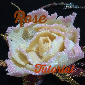 May include: A close-up of a beaded rose flower, made with white and pink beads. The rose is part of a beaded necklace and the text "Rose Tutorial" is visible in the image.