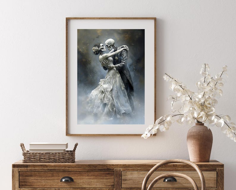 May include: Framed art print featuring a skeletal couple embracing in a romantic pose. The artwork depicts a man in a dark coat and a woman in a flowing white dress. The background has a misty, ethereal quality.