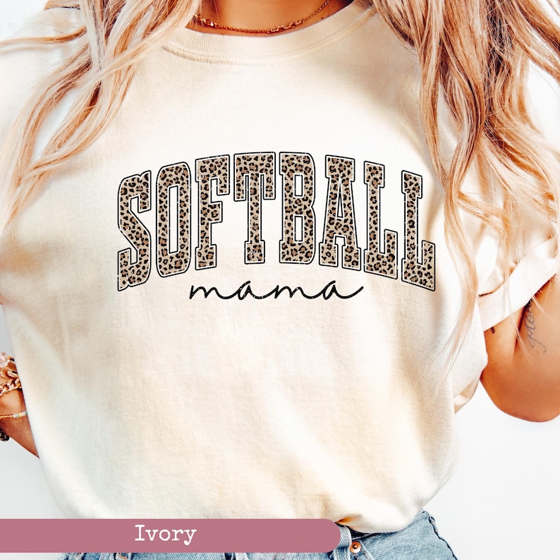 May include: Ivory t-shirt with a black and brown leopard print graphic that says "Softball mama".