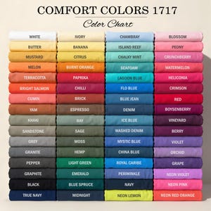 May include: A Comfort Colors 1717 color chart displaying four vertical columns of folded fabric swatches in various shades. Each swatch is labeled with its corresponding color name, ranging from white, yellow, and orange to blue, pink, and purple.