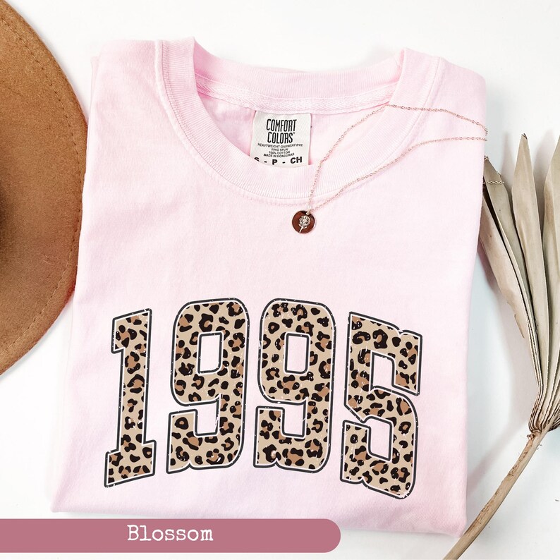 Op de afbeelding: Roze T-shirt met een luipaardprint van het jaar 1995. Het shirt heeft een witte omlijsting rond de cijfers.