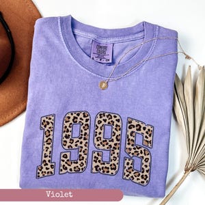 Op de afbeelding: Een paars T-shirt met een luipaardprint van het jaar 1995. Het shirt heeft een vintage look en is gemaakt van een zachte, comfortabele stof.